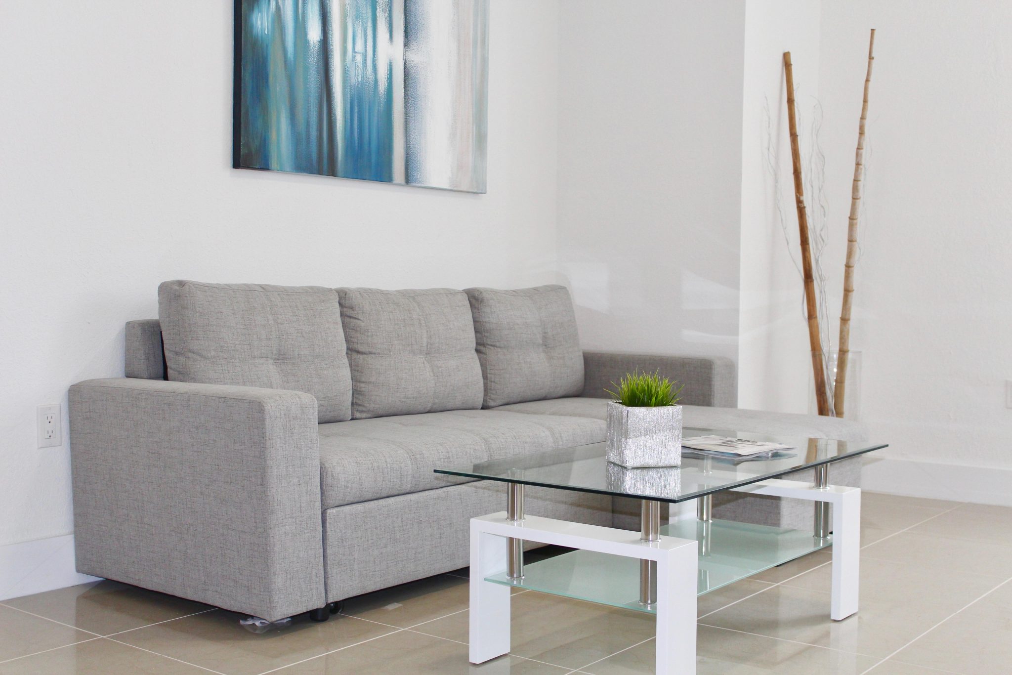 Bright living room with a sofa and blue artwork, published by Dental Design Smile as accommodation imagery